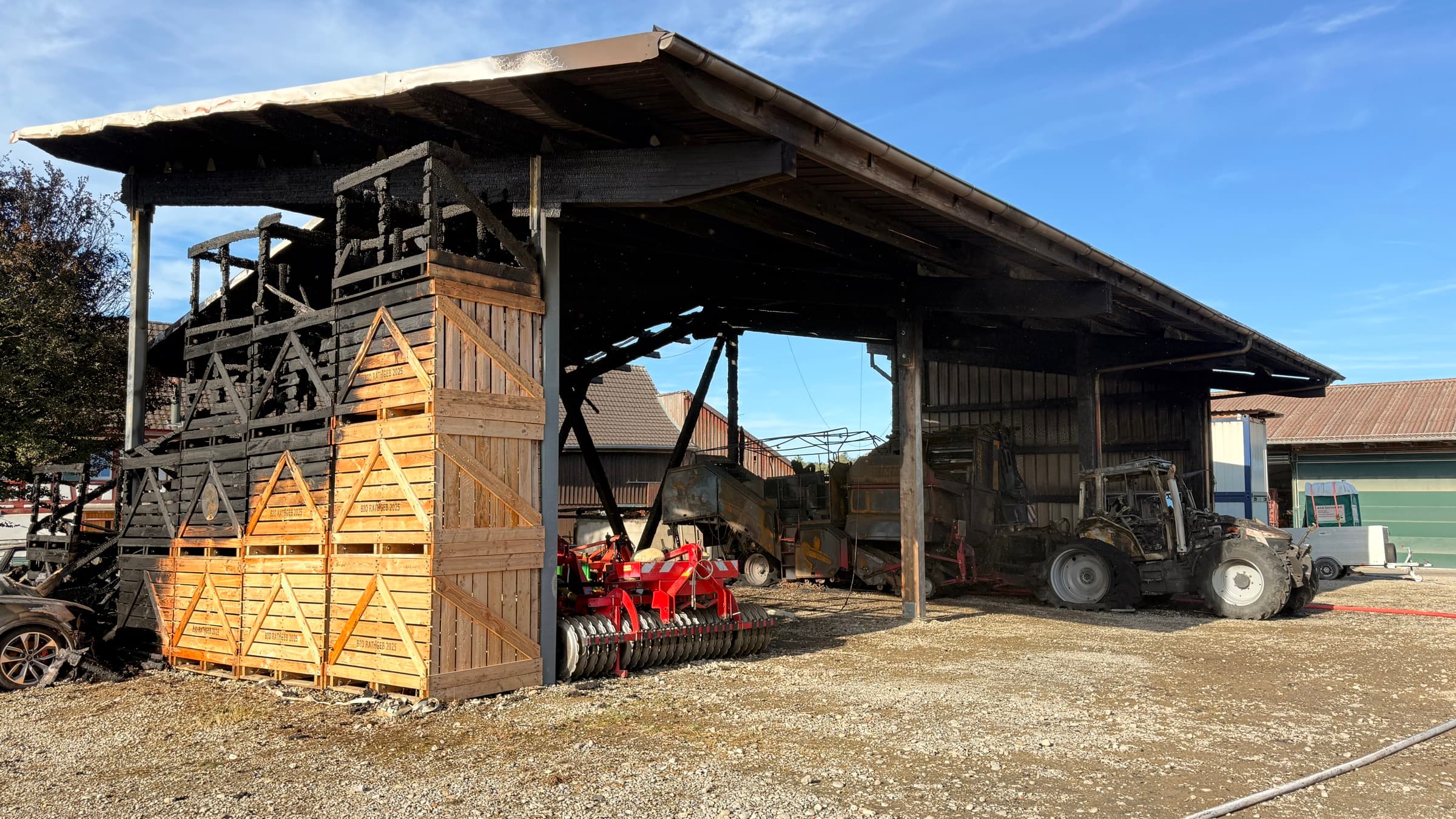 Die Halle nach dem Brand mit verkohltem Gebälk und neuen Holzpaloxen davor