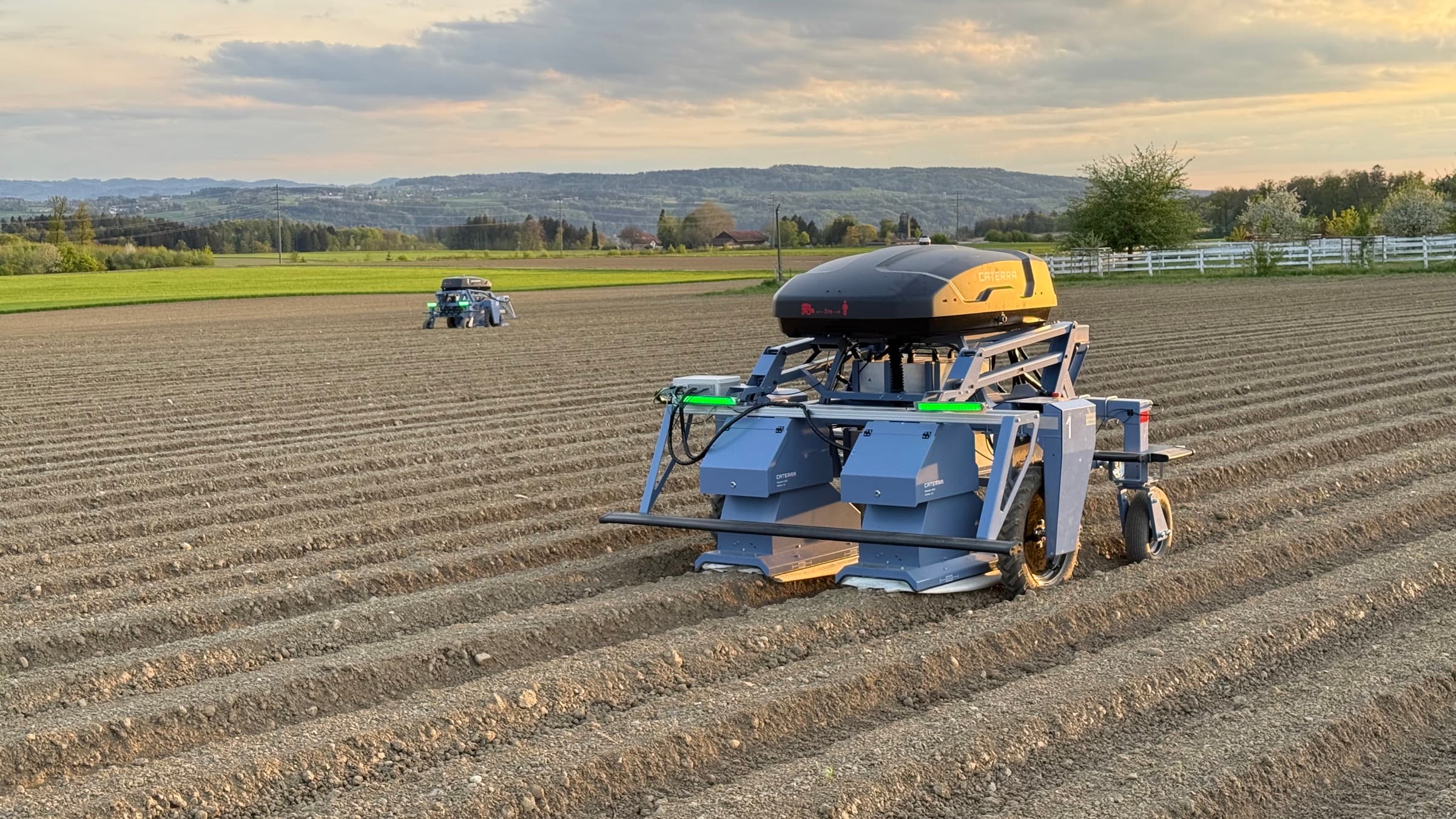 Autonomer Jätroboter auf einem Feld mit frisch gezogenen Dämmen, im Hintergrund ein zweiter